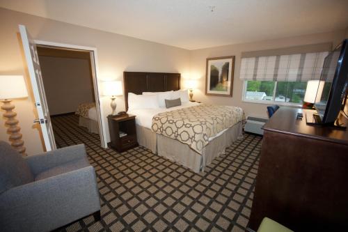 a hotel room with a bed and a living room at Baymont by Wyndham Erie in Erie