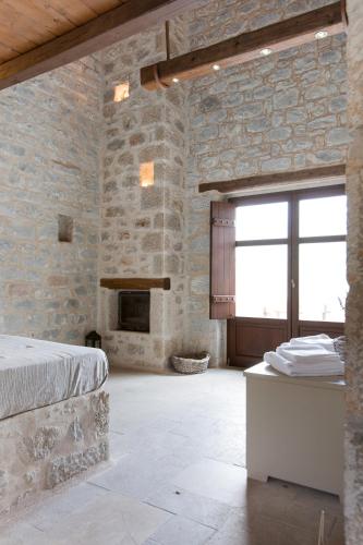 a stone walled bedroom with a bed and a fireplace at Petra & Fos Boutique Hotel & Spa in Neon Oitilon