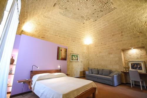 a bedroom with a bed and a couch and a brick wall at Domus Castrum in Bisceglie