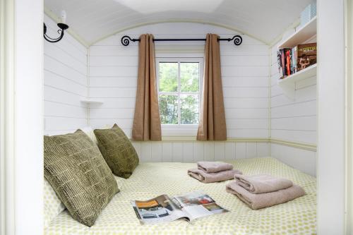a room with a bed with towels and a window at Romantic Shepherds Hut, Kenilworth in Kenilworth