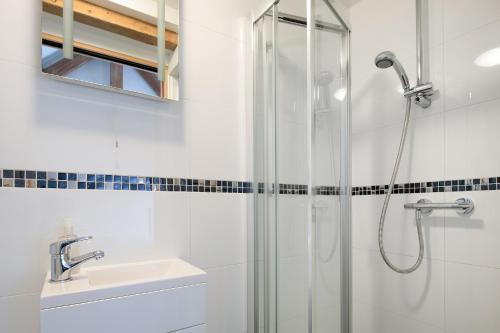 a white bathroom with a shower and a sink at The Cow Shed, Kenilworth, Sleeps 2 in Kenilworth