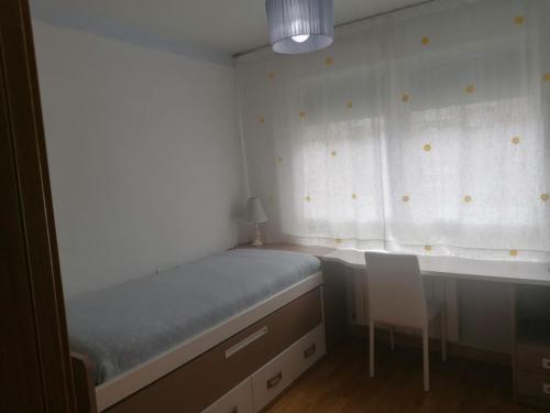 - une chambre avec un lit, une chaise et une fenêtre dans l'établissement Apartamento Praga, à Vitoria-Gasteiz