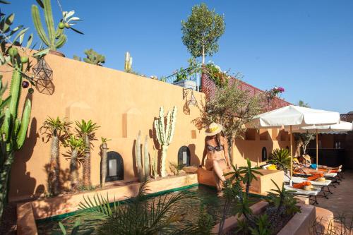 une femme assise à côté d'une piscine dans une maison dans l'établissement Riad Melhoun & Spa, à Marrakech