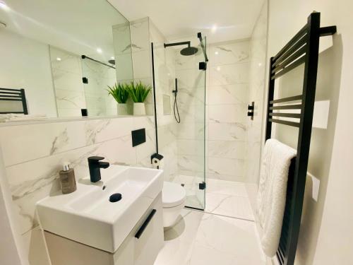 a white bathroom with a sink and a shower at 10 Bootham House - luxury city centre apartment with free parking for one car in York