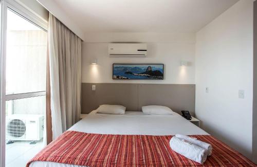 een slaapkamer met een groot bed en een rode deken bij Flat 804 - Conforto e vista panorâmica em Macaé in Macaé