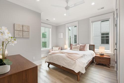 a white bedroom with a bed and two windows at The Palm Suite at 124 Spring in Charleston