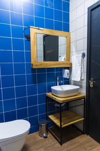 a blue tiled bathroom with a sink and a toilet at TJ GARDENS in Makhinjauri