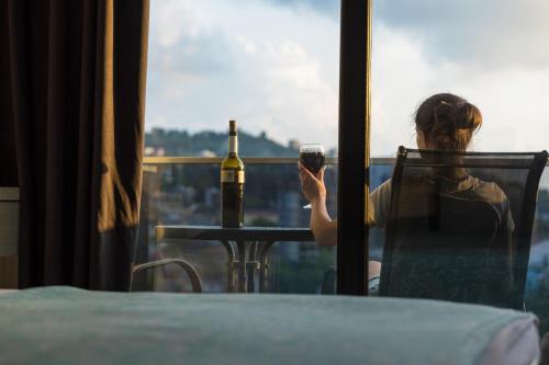 a woman sitting at a table with a bottle of wine at TJ GARDENS in Makhinjauri