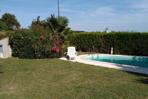 une chaise blanche assise à côté d'une piscine dans l'établissement Joli studio indépendant avec jardin et piscine partagés, à Arces-sur-Gironde