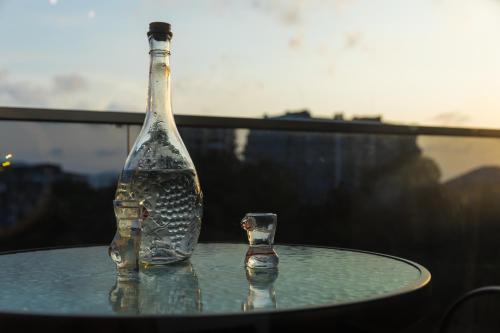 a glass bottle sitting on top of a table next to a glass at TJ GARDENS in Makhinjauri