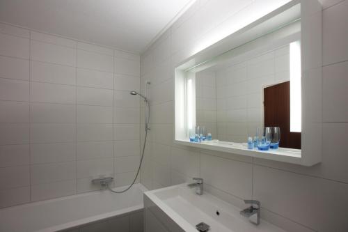 La salle de bains est pourvue d'une baignoire, d'un lavabo et d'un miroir. dans l'établissement Hotel Restaurant Riche, à Boxmeer