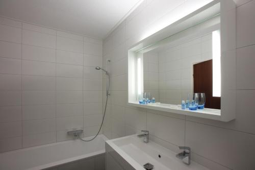 ein Badezimmer mit einer Badewanne, einem Waschbecken und einem Spiegel in der Unterkunft Hotel Restaurant Riche in Boxmeer