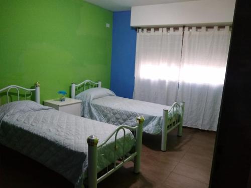 2 camas en una habitación con paredes verdes en Casa Centrica Lujan Planta Alta en Luján