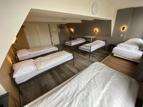 a room with three beds and a table at Xplore Hostel Amsterdam in Amsterdam