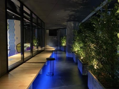 a hallway with blue lights in a building with plants at HOTEL TAVINOS Kyoto in Kyoto