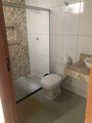 a bathroom with a toilet and a glass shower at Casa Siqueira Nova Viçosa in Nova Viçosa