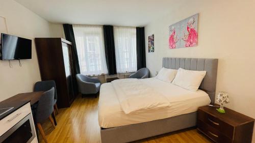 a bedroom with a bed and a desk and a television at Akomo Bern in Bern
