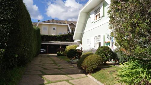 a white house with a walkway in the yard at Pousada Chateau Colinas in Campos do Jordão