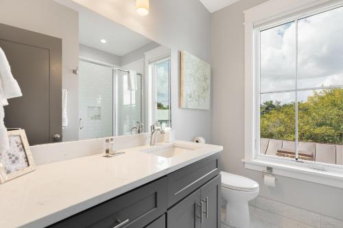 een badkamer met een wastafel, een toilet en een raam bij The Azalea Suite at 124 Spring in Charleston