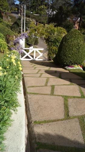 a stone pathway with a white bench in a garden at Pousada Chateau Colinas in Campos do Jordão