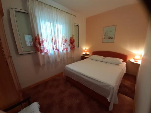 ein Schlafzimmer mit einem Bett und einem Fenster mit zwei Lampen in der Unterkunft HOUSE-APARTMENTS ELA -MIRCA- FAMILY HOLIDAY in Mirce