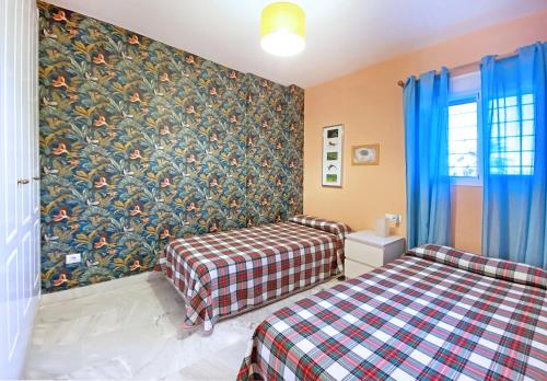 イスランティージャにあるFANTASTICAS VISTAS, apartamento ideal para familias con niños, Naturaleza, sol y playa en Islantillaのベッドルーム1室(ベッド2台付)が備わります。壁に壁画が飾られています。