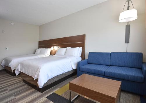 a hotel room with two beds and a blue couch at Holiday Inn Express & Suites - Orlando - Southeast, an IHG Hotel in Orlando
