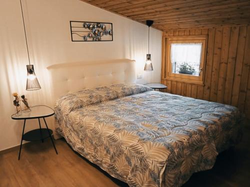 1 dormitorio con 1 cama, 2 mesas y una ventana en La Mansarda en Lozzo Cadore