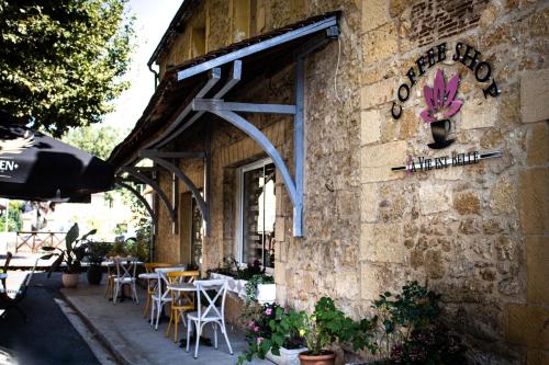 a stone building with tables and chairs outside of it at Appart Hôtel La vie est belle in Lalinde