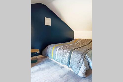 a bedroom with a bed and a blue wall at Petite maison de charme in Doué-la-Fontaine