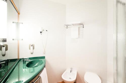 La salle de bains est pourvue d'un lavabo vert et de toilettes. dans l'établissement Ibis Roma Fiera, à Rome