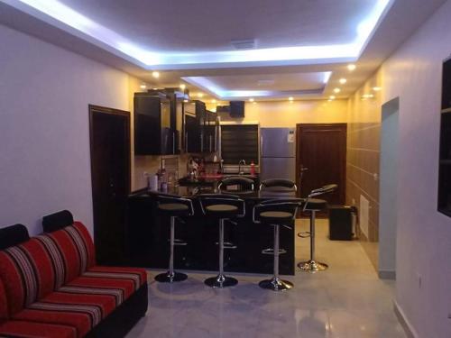 a kitchen with a bar with stools and a red couch at Petra Desert Dream Hotel in Wadi Musa