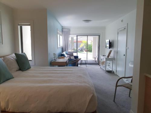 a bedroom with a large bed and a living room at Peaceful Mount Studio Moments to Beach & Downtown in Mount Maunganui