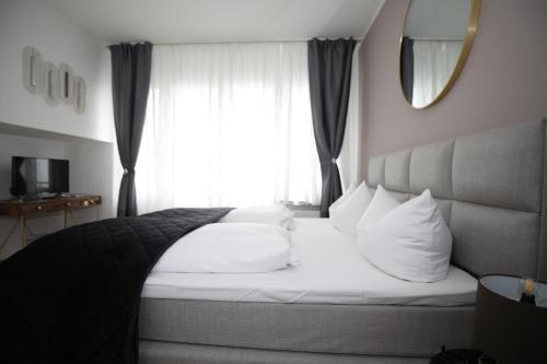 a bedroom with a bed with white pillows and a window at TM Hotel Düsseldorf in Düsseldorf
