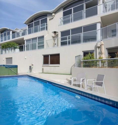 a house with a swimming pool next to a building at Modern Beach Apartment with Pool & Location in Mount Maunganui
