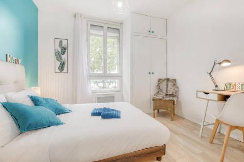 a bedroom with a white bed with blue pillows and a desk at Superbe appartement tout près de Paris in Alfortville