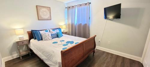 Un dormitorio con una cama con un televisor en la pared. en Seaside Gem, en Biloxi
