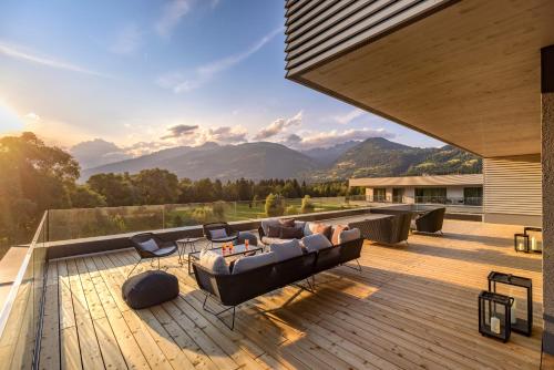 a patio with a couch and chairs on a deck at Dolomitengolf Suites in Lavant