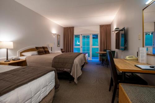 a hotel room with two beds and a desk at Wallaceville Motor Lodge in Upper Hutt