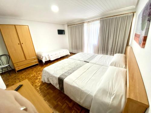 a bedroom with a large white bed and a window at Garden Lodge Hostal Evencio in Ribadavia