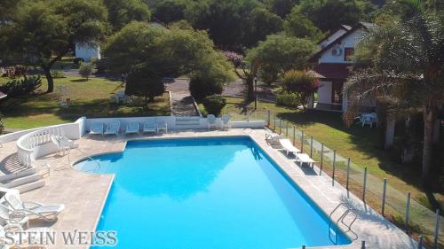 a large swimming pool with chairs and a house at Cabañas Stein Weiss in Santa Rosa de Calamuchita