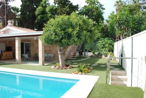 un patio con piscina y un árbol junto a una casa en CASA VACACIONAL MÁLAGA 14 Chalet en Málaga