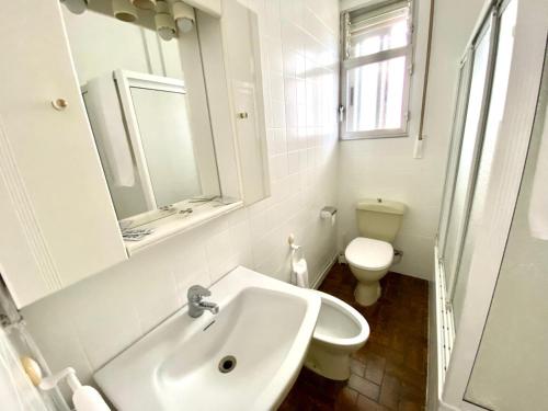 a white bathroom with a sink and a toilet at Garden Lodge Hostal Evencio in Ribadavia