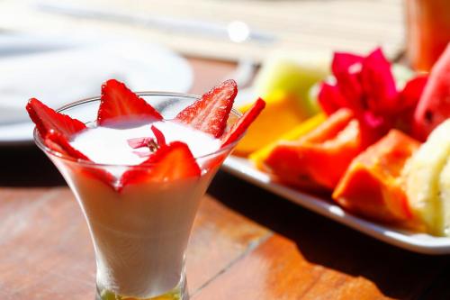 a drink with strawberries and a plate of fruit at Pousada Tatuá in Pôrto de Pedras