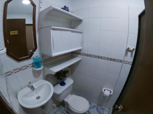 een badkamer met een wastafel, een toilet en een spiegel bij Casa Olimpico Hostal in Cali