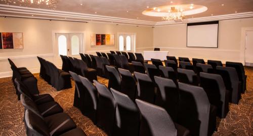 a conference room with black chairs and a screen at Gold Reef City Theme Park Hotel in Johannesburg