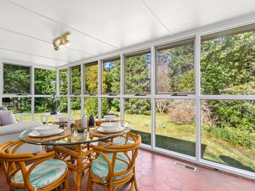 a dining room with a table and chairs and large windows at Linden in Mount Wilson