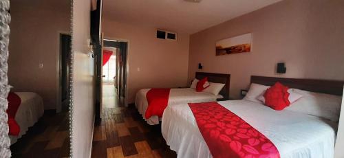 a bedroom with two beds with red and white sheets at Casa Gaviota Dorada in Baños