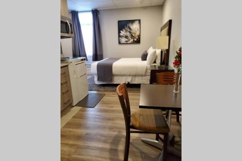 a bedroom with a bed and a table and a kitchen at Cozy Sweet Studio #7, 10 minutes to D.T. Ottawa in Gatineau