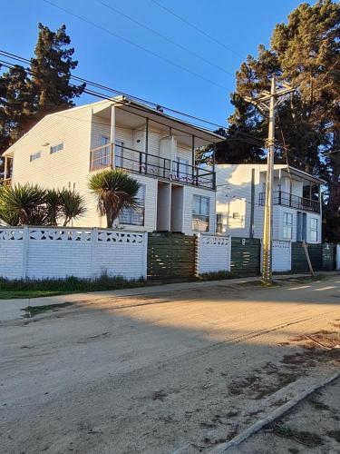 uma casa branca com uma cerca à frente. em Cabañas Costa Norte em Algarrobo